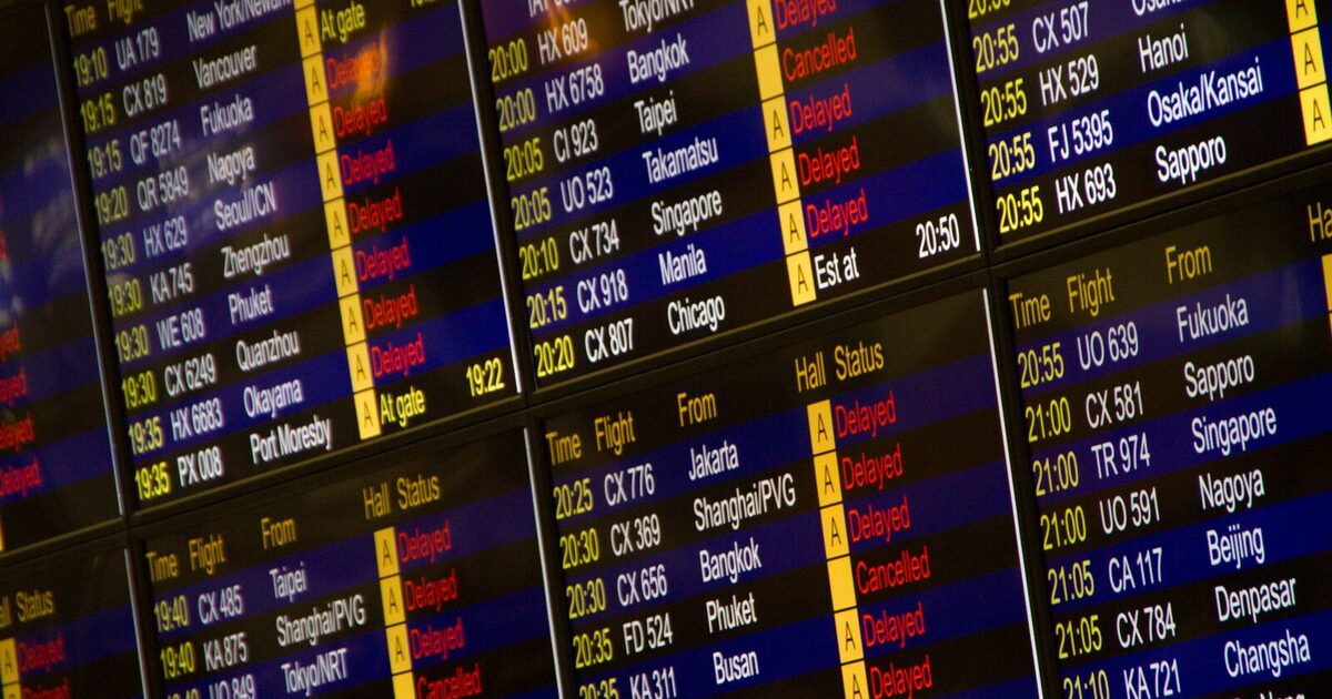 Close-up of an international airport departures board showing several flights marked Delayed and Cancelled in red